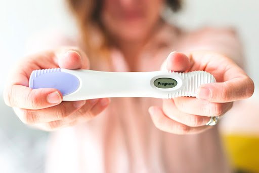 Mãe segurando teste de gravidez positivo. Sinais de gravidez